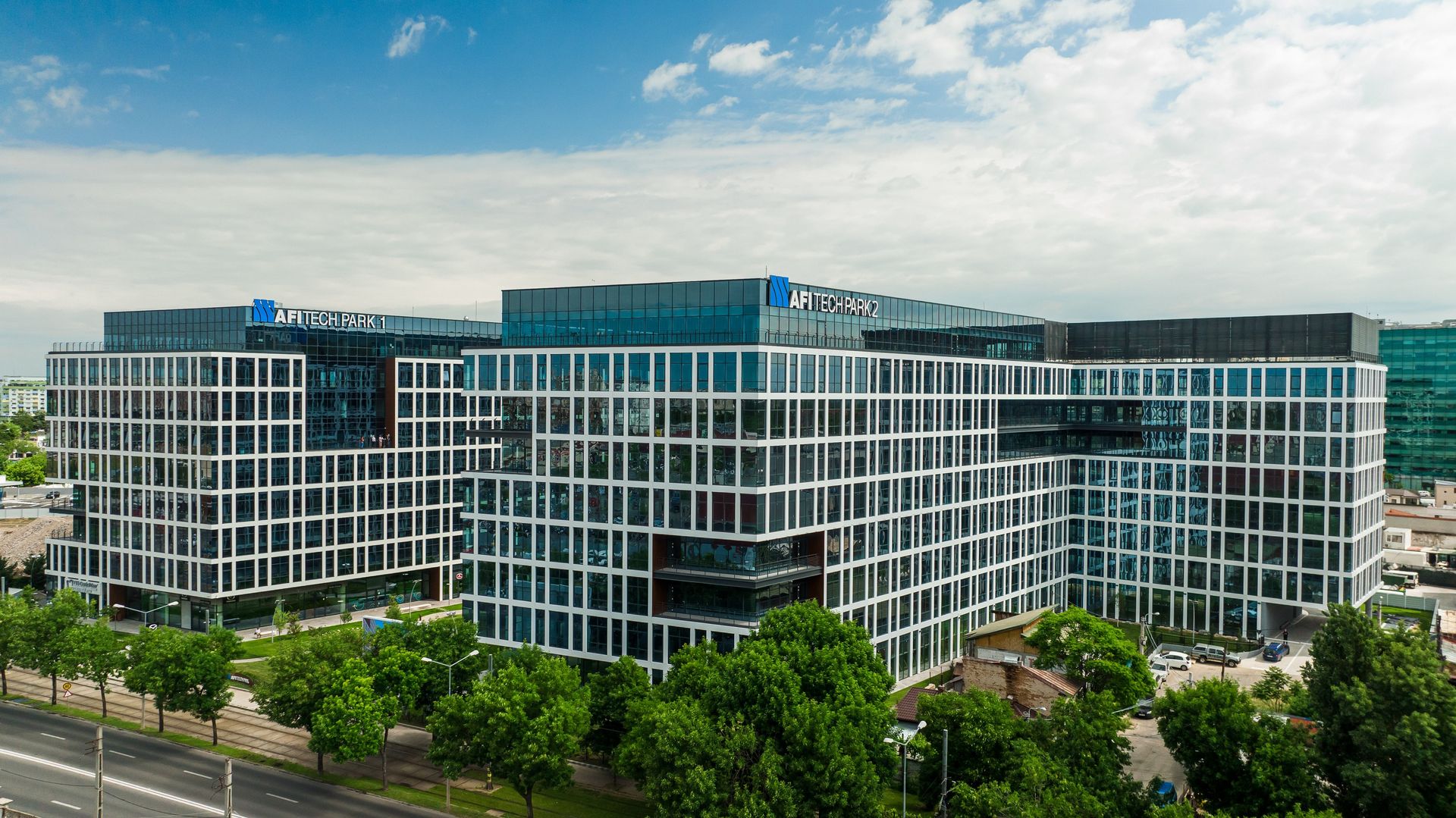 Clădirile de birouri AFI Tech Park 1 și 2, cu fațade albe în grilă și copaci în prim-plan, sub un cer cu nori